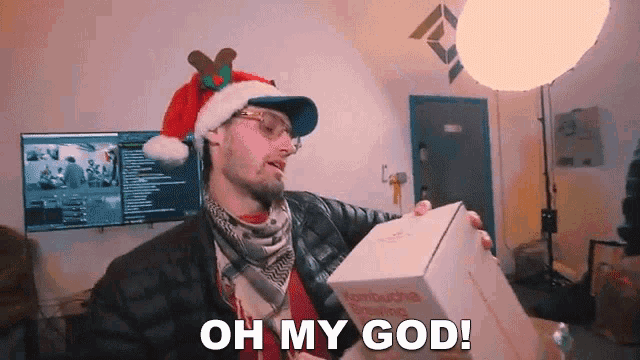 a man wearing a santa hat and glasses is holding a box and says oh my god