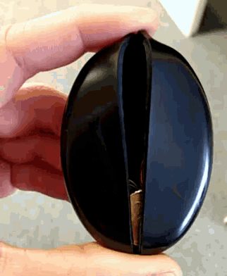 a person is holding a black coin holder with a coin inside