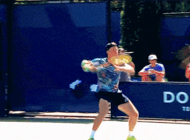 a man is playing tennis in front of a blue wall that says do