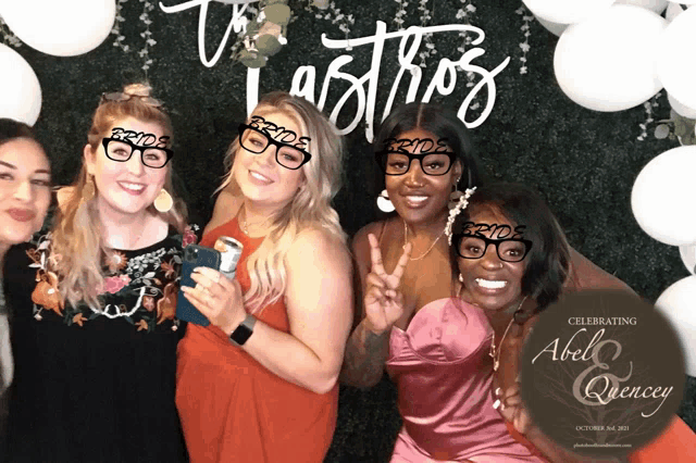 a group of women pose for a photo in front of a sign that says celebrating abel and quincy