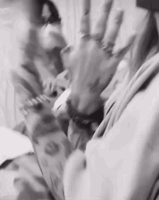 a black and white photo of a person 's hands with rings