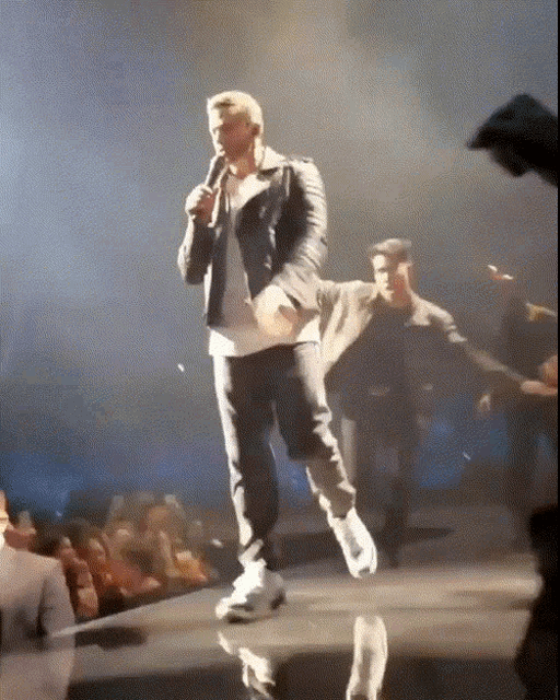 a man singing into a microphone on a stage