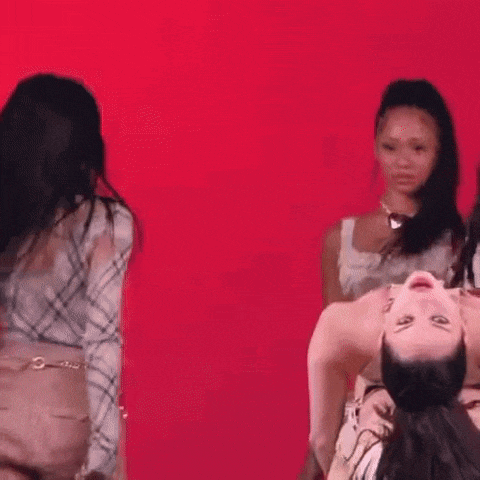three women are dancing in front of a red background .