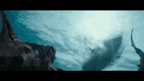 a whale is swimming in the ocean near a rock