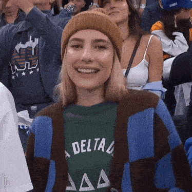 a woman wearing a delta shirt is smiling in a crowd of people