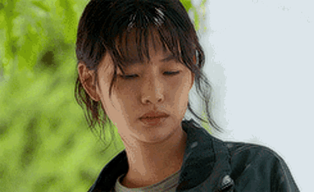 a close up of a woman 's face with her eyes closed wearing a jacket .