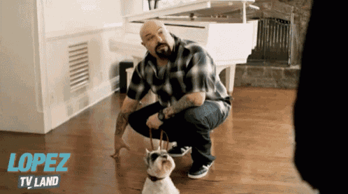 a man kneeling down next to a small dog with the word lopez tv land on the bottom right