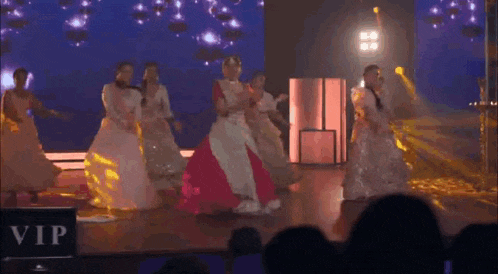 a group of women are dancing on a stage in front of a large screen .