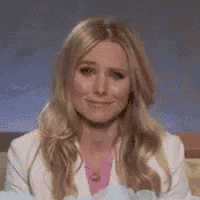 a woman with long blonde hair and a white jacket is smiling .