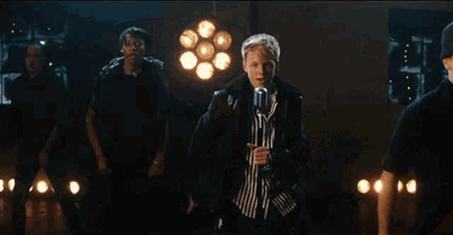 a man in a striped shirt is singing into a microphone