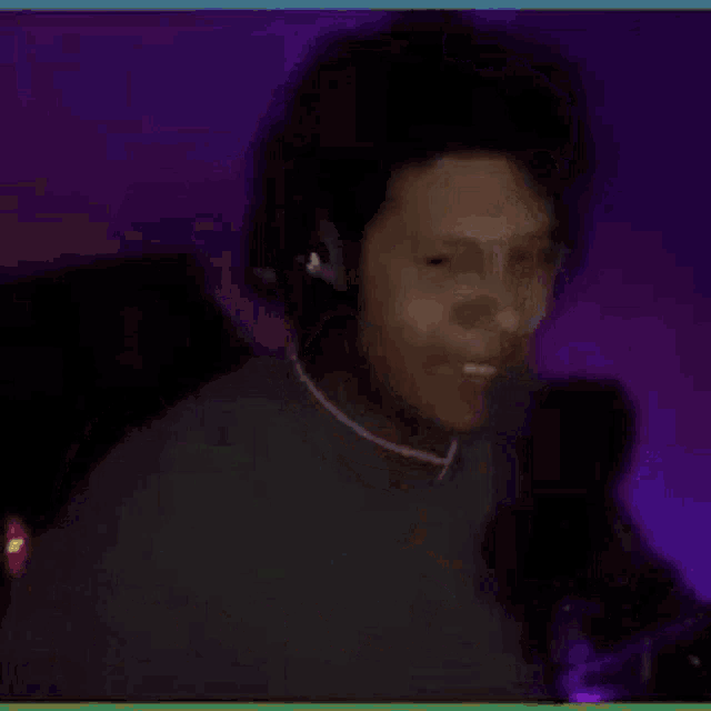 a man wearing headphones is sitting in front of a microphone and covering his mouth .