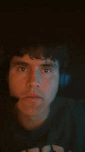 a man wearing headphones and a t-shirt with the letter h on it looks surprised