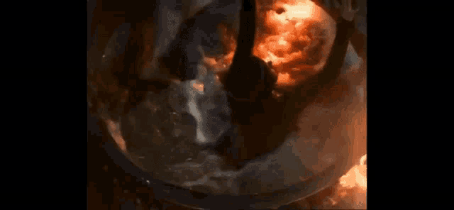 a person is standing in a large bowl of water with fire coming out of it .