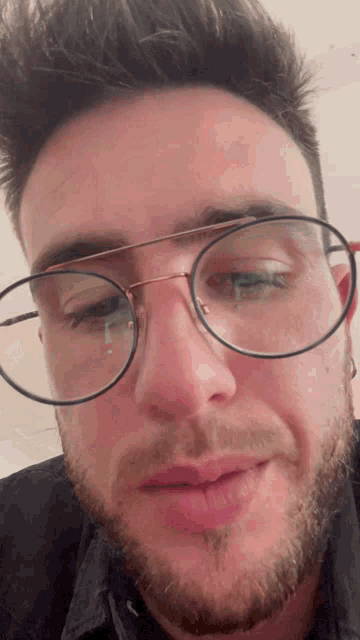 a man with glasses and a beard looks at the camera