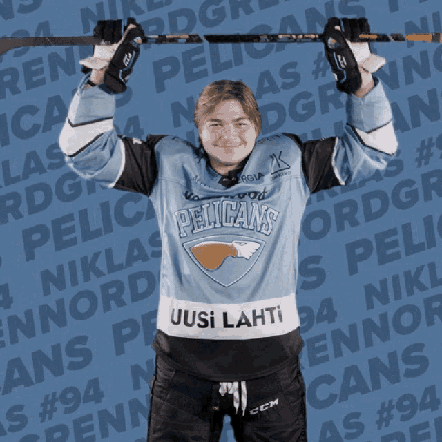 a pelican 's hockey player is holding a stick over his head