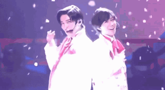 two young men are standing next to each other on a stage .
