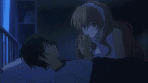 a boy and a girl are laying in bed and the girl is touching the boy 's hand