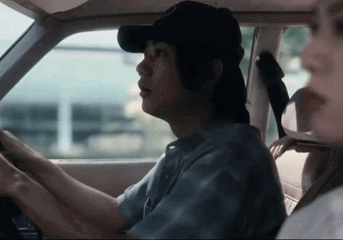 a man wearing a hat is driving a car next to a woman