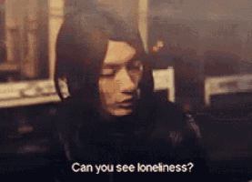a man with long hair is looking down and says can you see loneliness