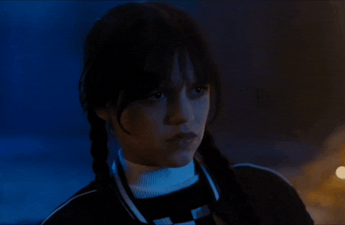 a girl with pigtails is looking at the camera in a dark room