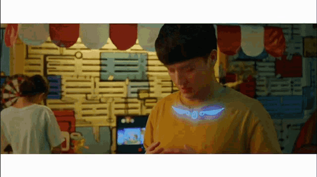 a young man in a yellow shirt has a glowing wing on his chest