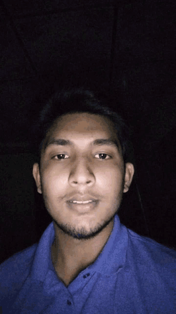 a young man in a blue shirt looks at the camera