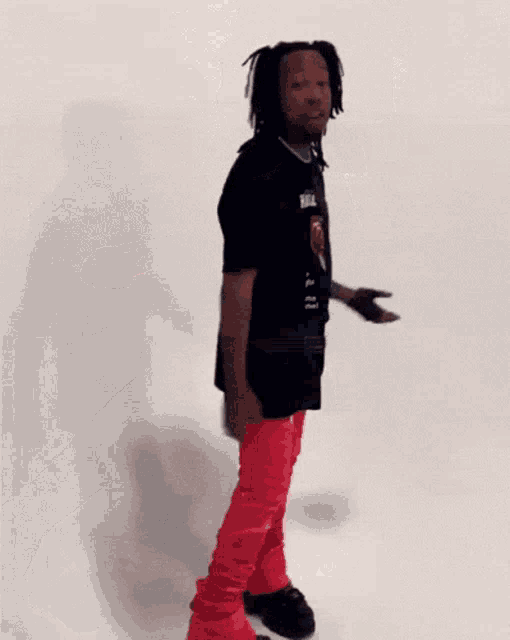 a man wearing a black shirt and red pants is dancing .