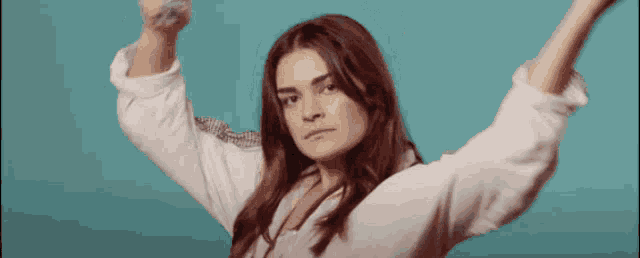 a woman in a white shirt holds her arms in the air