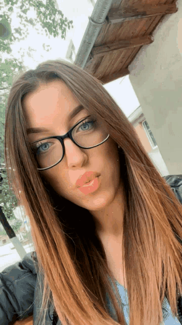 a woman wearing glasses is taking a selfie with her mouth open