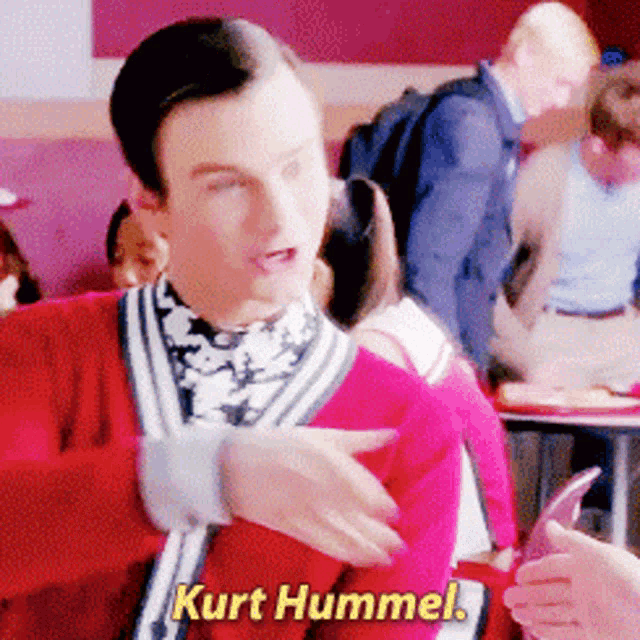 a man in a red sweater says kurt hummel in yellow letters