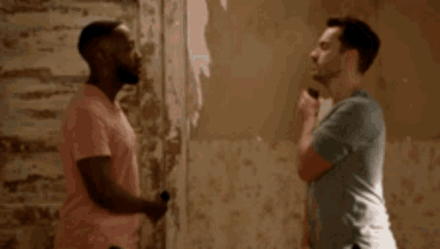 two men are standing next to each other and talking in a room .