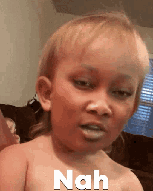 a baby without a shirt has the word nah written on his face