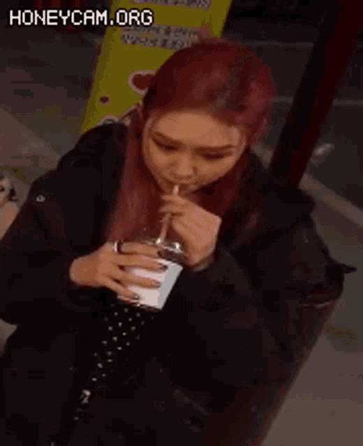a woman with red hair is holding a glass of water with a pink straw .