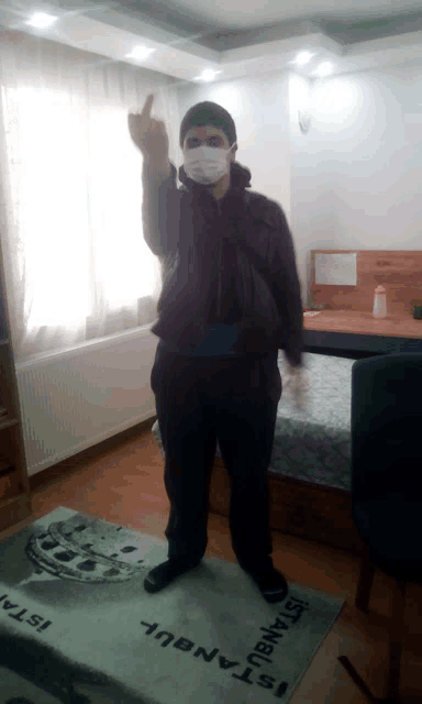 a man wearing a face mask stands in front of a rug that says istanbul