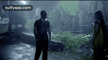 a man and woman are standing next to each other in the rain .