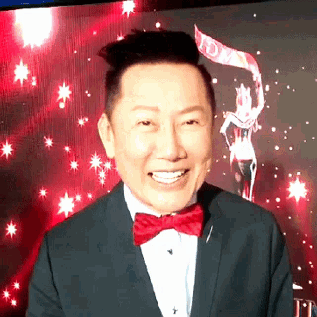 a man in a suit and bow tie is smiling in front of a screen that says ' td ' on it