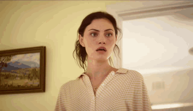 a woman is standing in front of a framed picture on the wall