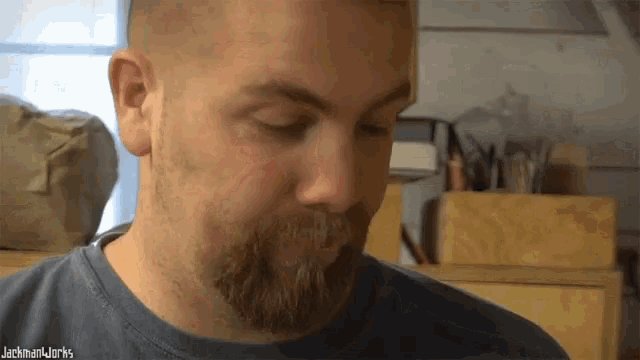 a man with a beard wearing a blue shirt that says jackman works