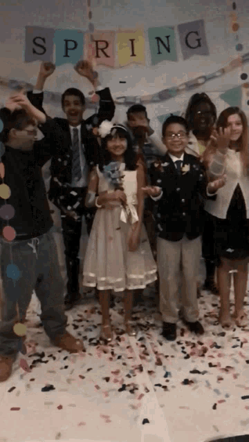 a group of children are posing in front of a banner that says spring