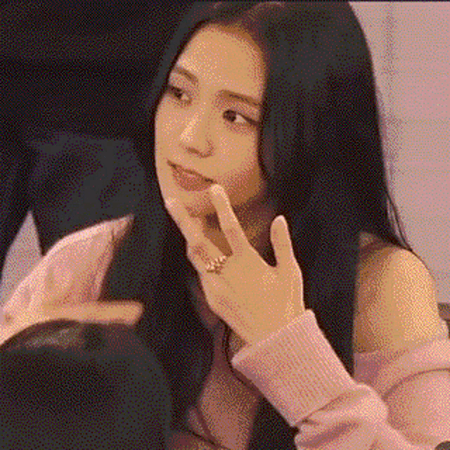 a woman with long black hair and a ring on her finger is sitting on a couch .