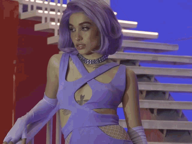 a woman with purple hair is wearing a purple top