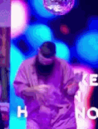 a man in a purple jacket is standing in front of a disco ball and a sign that says " h no "