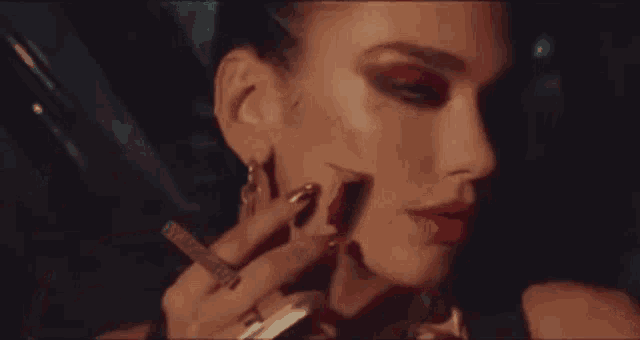a woman is applying red lipstick to her face while holding a lipstick .