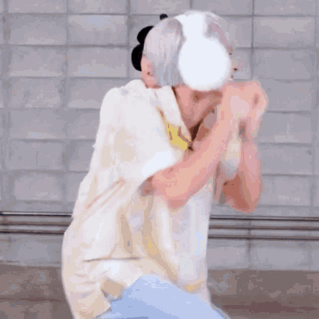 a person wearing headphones is holding a white object in front of their face