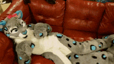 a stuffed animal laying on a red couch with a bow on its head