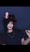 a girl wearing a black cat hat with a pink flower on it .