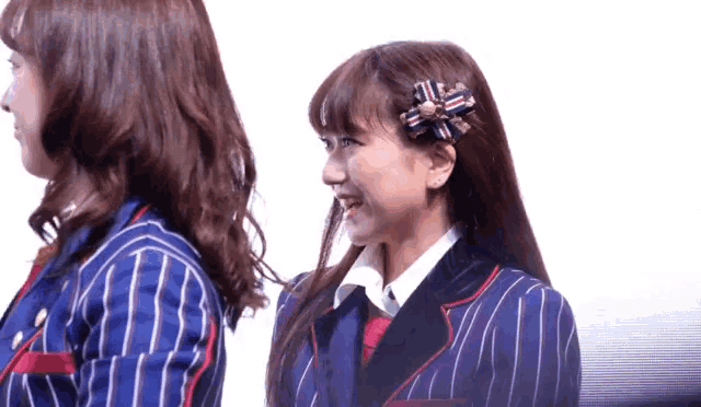 two girls in striped suits are standing next to each other and smiling .