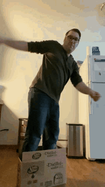 a man is standing on a cardboard box that says distilled water