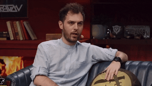 a man sits on a couch in front of a sign that says arrow on it