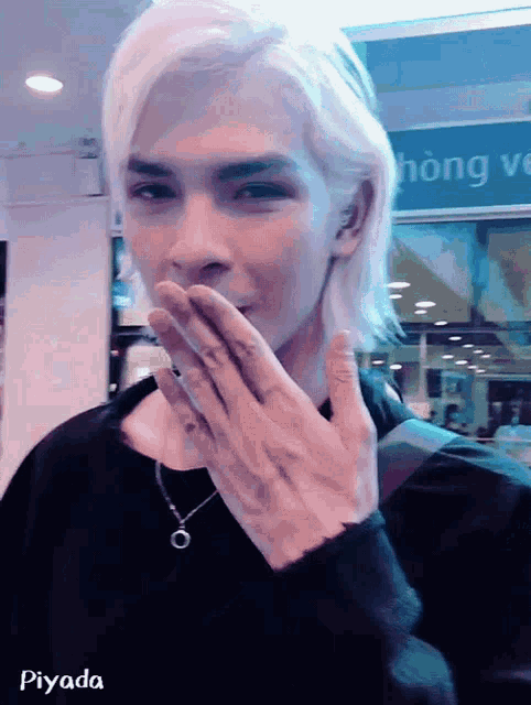 a man with blonde hair is covering his mouth with his hands and the word piyada is on the bottom